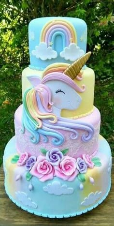 a three tiered cake with an unicorn on top and roses around the edges, all decorated in pastel colors