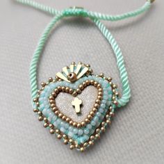 a beaded necklace with a heart and cross hanging from it's side on a blue cord