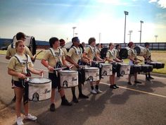 a group of people that are standing in the street with some drums