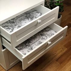 two drawers are open on the floor next to a potted plant