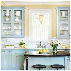 a kitchen with blue cabinets and marble counter tops, two stools in front of the island