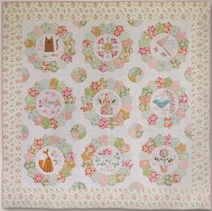 a quilted wall hanging with many different designs on it's sides and an orange cat sitting in the center