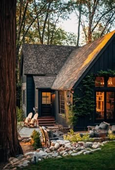 a black house with trees and rocks in front