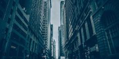 an empty city street with tall buildings on both sides and people walking down the sidewalk