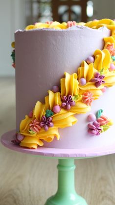 there is a cake decorated with flowers and ribbons on the top of this cake stand