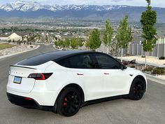 a white sports car parked on the side of a road with mountains in the background