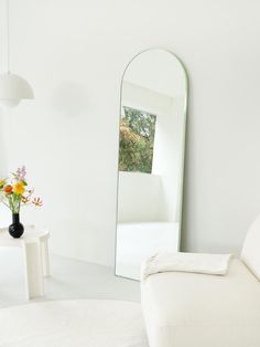 a living room with white furniture and a large mirror