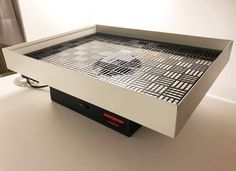 an apple computer sitting on top of a white table with black and red squares in it