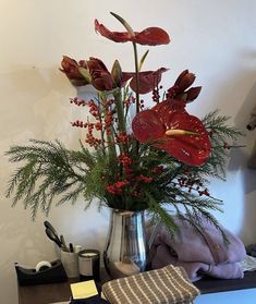 a vase filled with red flowers sitting on top of a table next to other items