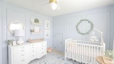 a baby's room with a crib, dresser and wall hanging in the corner