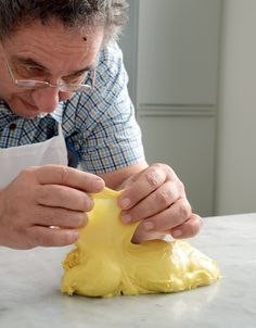 a man in glasses is decorating a yellow object on a table with white paper