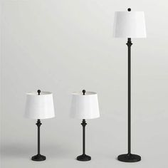 three lamps with white shades on them and one lamp is black, the other is white