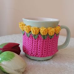 a knitted coffee cup cozying next to an onion on a white tablecloth