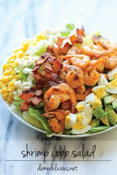 shrimp cobb salad with corn and avocado in a white bowl on a marble surface