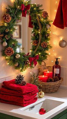 a christmas wreath is hung on the wall above a sink with red towels and pine cones