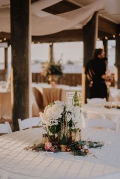 the table is set up with flowers and greenery for an elegant wedding reception at the beach