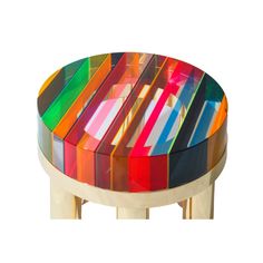 a multicolored table with gold legs and a glass top that has stripes on it