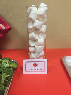 a table topped with a vase filled with marshmallows and broccoli