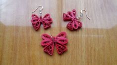 two pink crocheted butterfly earrings sitting on top of a wooden table next to each other