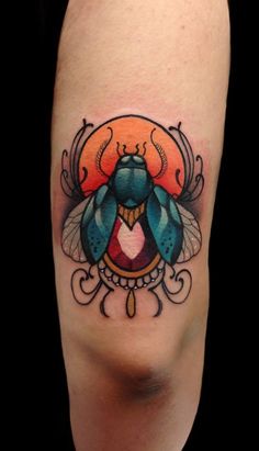 a colorful tattoo on the leg of a woman's legs, with a blue and orange beetle