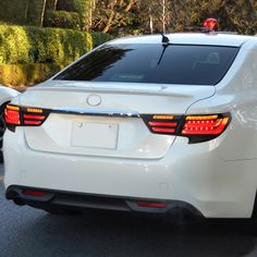 the back end of a white car with its lights on