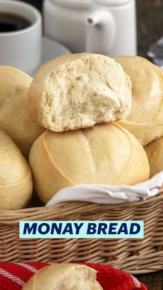 a basket full of rolls sitting on top of a table next to two cups of coffee