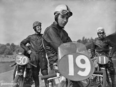 black and white photograph of three men on motorbikes with number 19 sign in foreground