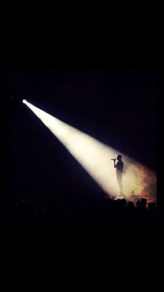 a person standing on top of a stage holding a microphone in front of a crowd