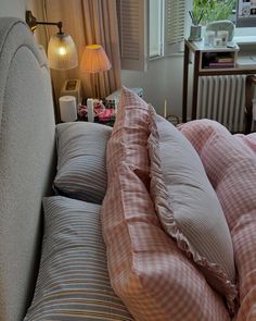 a bed that has some pillows on it and a lamp next to the headboard