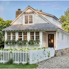 a white house with flowers on the windows and a picket fence around it's perimeter