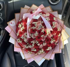 a bouquet of red and pink roses in the center of a car's steering wheel