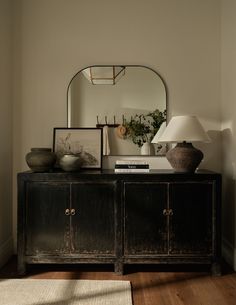 a black cabinet with two vases and a mirror on it's sideboard