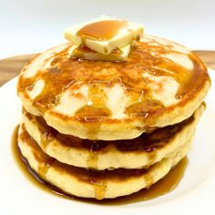 stack of pancakes covered in syrup and butter on top of a white plate with caramel sauce