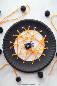 a paper plate that has some orange sticks on it and a black cat in the center