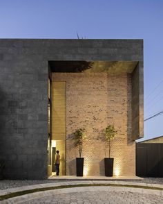 an entrance to a brick building with potted plants on the outside and a man standing in the doorway