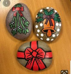 three painted rocks with bows on them sitting on top of a wooden table next to each other