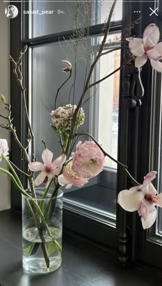 two vases filled with flowers sitting on a window sill next to a window