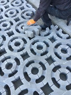 a man kneeling down on top of a cement floor next to an orange rubber glove