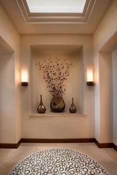 two vases with flowers are on the wall above a rug in a room that has light colored walls and flooring