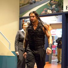 a man with long hair and no shirt is walking down the stairs in front of a building