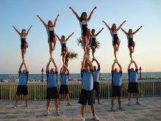 a group of people standing on top of each other with their hands in the air