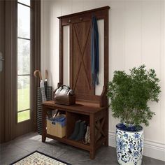 a wooden bench sitting next to a potted plant on top of a rug in front of a window