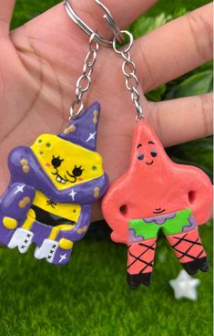 two cartoon characters are hanging from a keychain in the palm of someone's hand