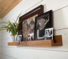 some pictures are hanging on the wall above a couple's photos and a potted plant