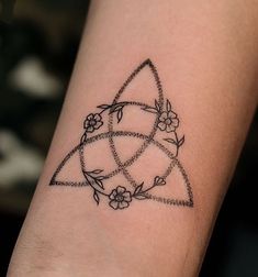 a tattoo on the arm of a woman with flowers and triangles around her wrist,