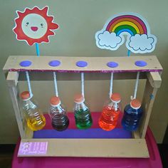 an assortment of different colored liquids in plastic bottles on a pink cart with rainbow stickers