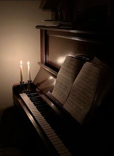 a piano with sheet music and two candles