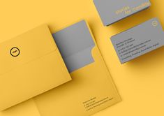 two envelopes with business cards on them sitting next to each other in yellow and grey