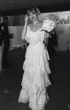 black and white photo of woman in dress walking down the street with flowers on her head