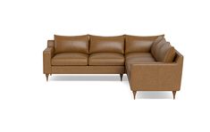 a brown leather sectional sofa sitting on top of a white floor next to a chair